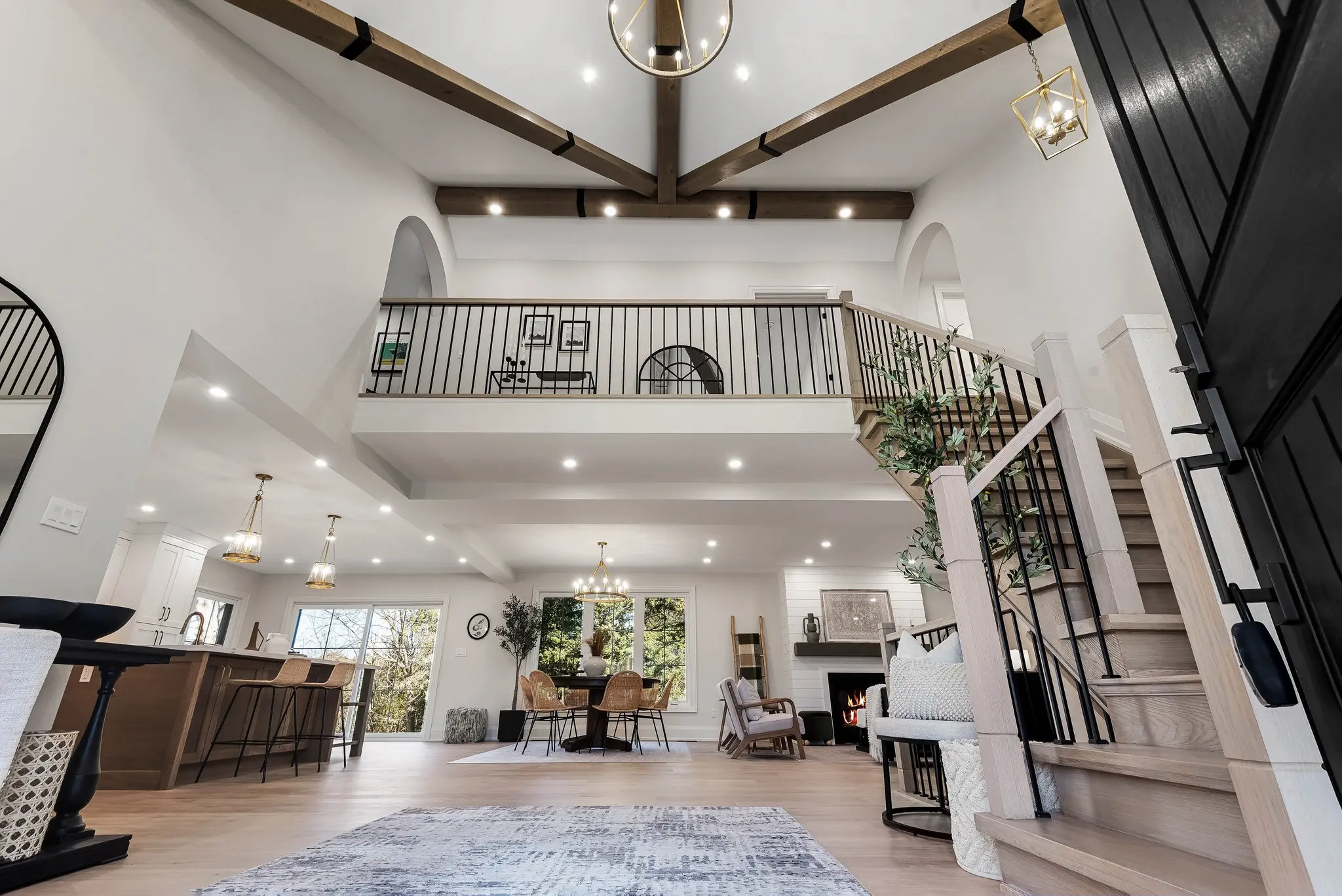 Grand open-concept great room in an Oshawa home, featuring soaring ceilings with exposed wood beams, a mezzanine, and a modern staircase.